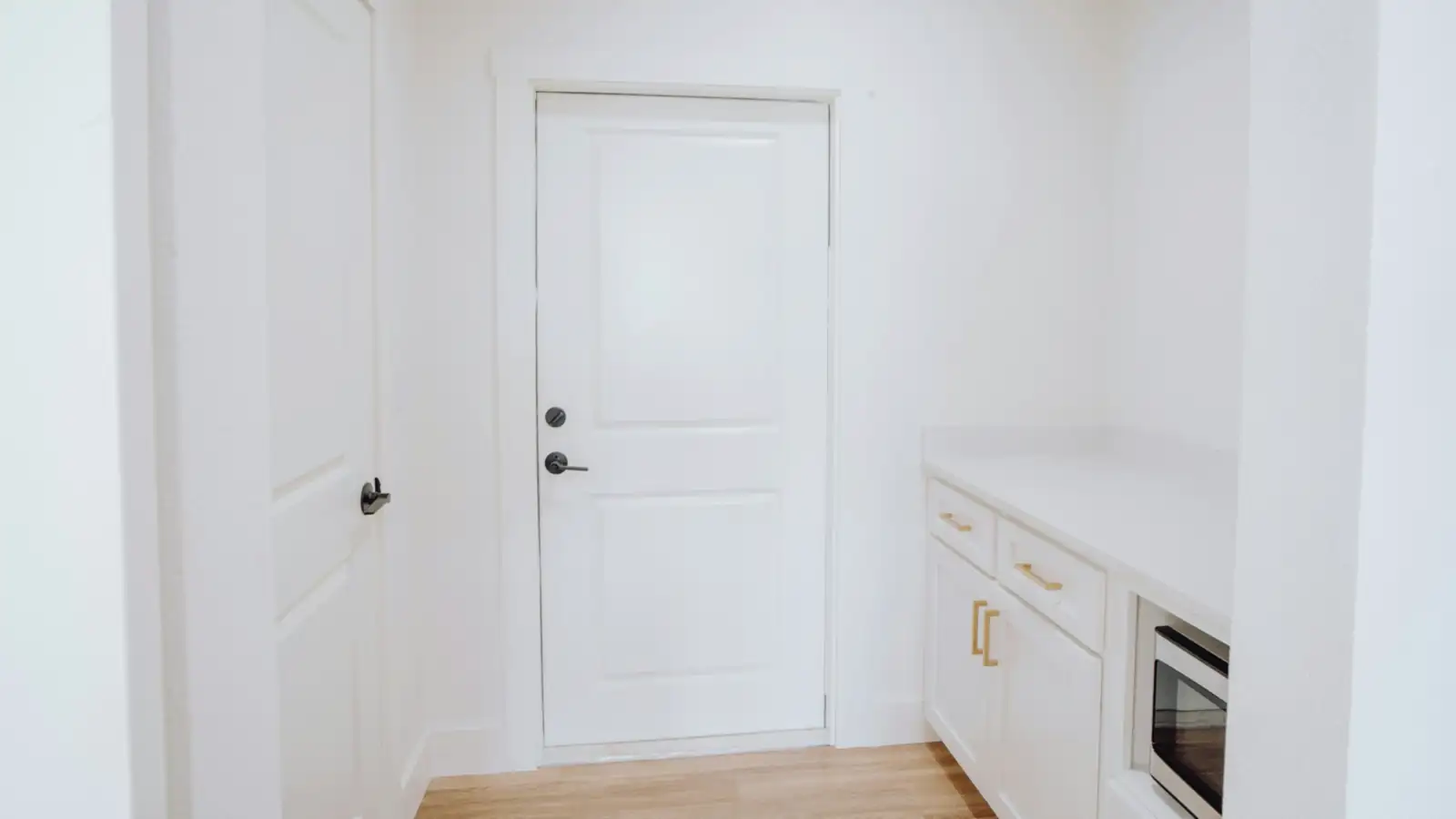 Pasillo de una vivienda con puertas de paso blancas y la cocina al fondo